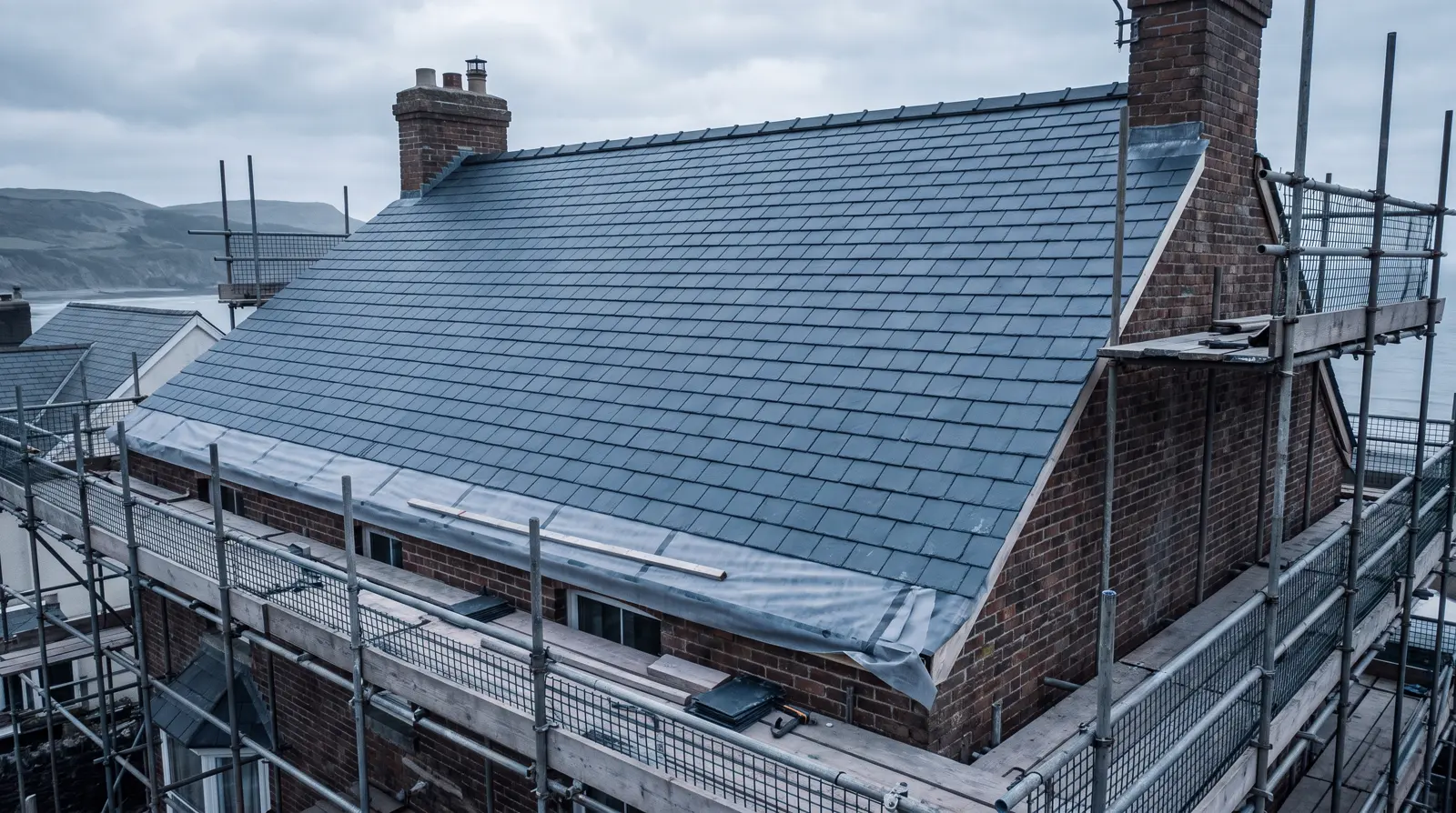 Newly completed pitched slate roof on a detached brick house